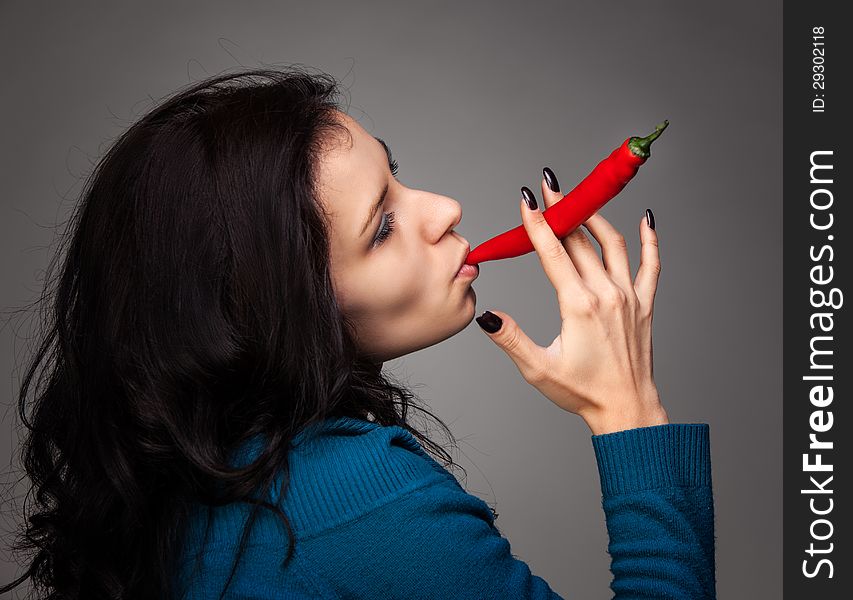 Young lady holding red hot chili pepper in mouth. Young lady holding red hot chili pepper in mouth