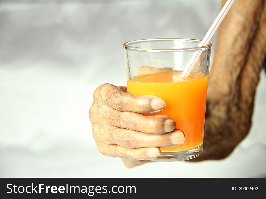 An old aged hand holding a glass of orange juice. An old aged hand holding a glass of orange juice