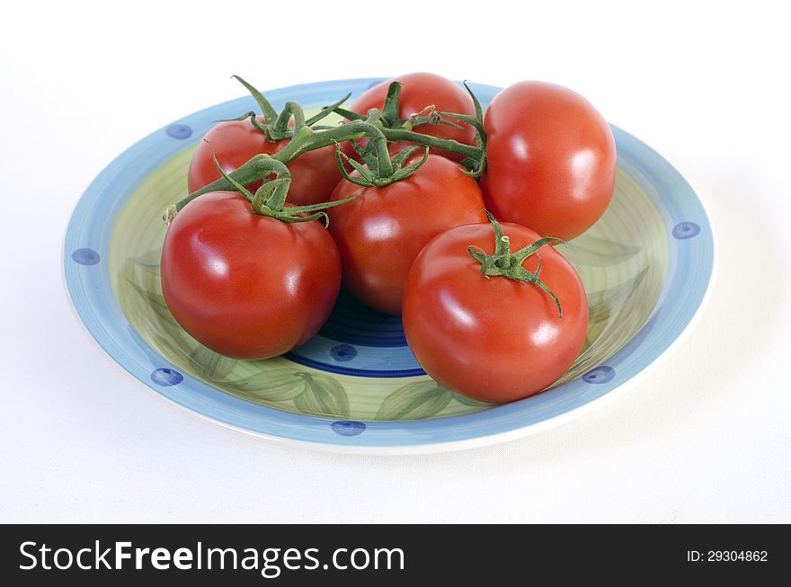 Closeup of tomatoes on the vine in a plate isolated on white background