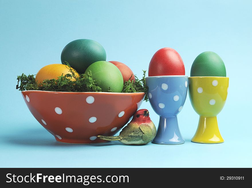 Bright and cheerful Happy Easter still life with rainbow color eggs in orange polka dot bowl against a blue background. Bright and cheerful Happy Easter still life with rainbow color eggs in orange polka dot bowl against a blue background.