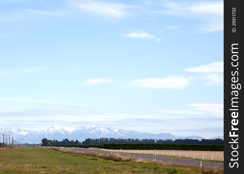 Long road stretching out into the distance with snow mountain background in New Zealand