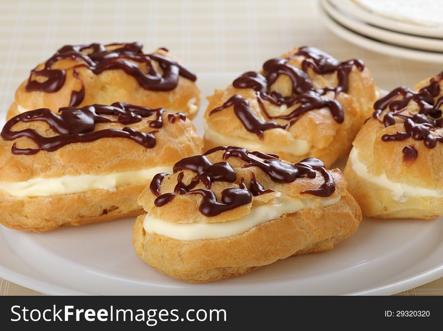 Chocolate eclairs with cream filling on a platter