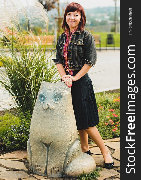 Young woman standing near funny cat statue