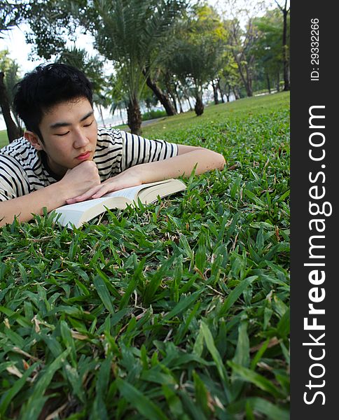 Young handsome guy reading in the park.