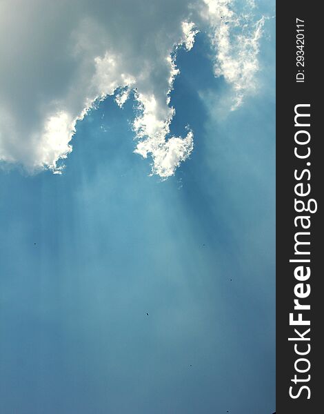 a burst of sunlight with a background of blue sky and dark clouds
