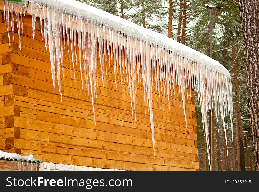 Row of icicles from the roof of the wooden house