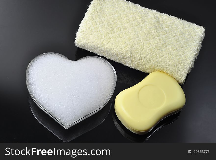A heart made of foam, and a soap and a towel on black background. A heart made of foam, and a soap and a towel on black background