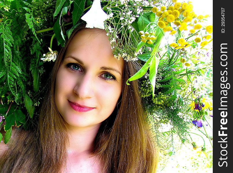 A girl in a wreath of flowers and herbs summer