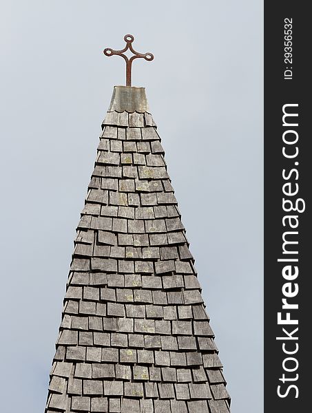 An old cross on top of an old wooden tile roof