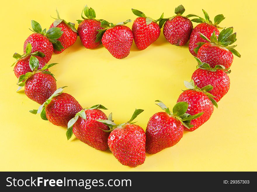 Strawberries heart on yellow background