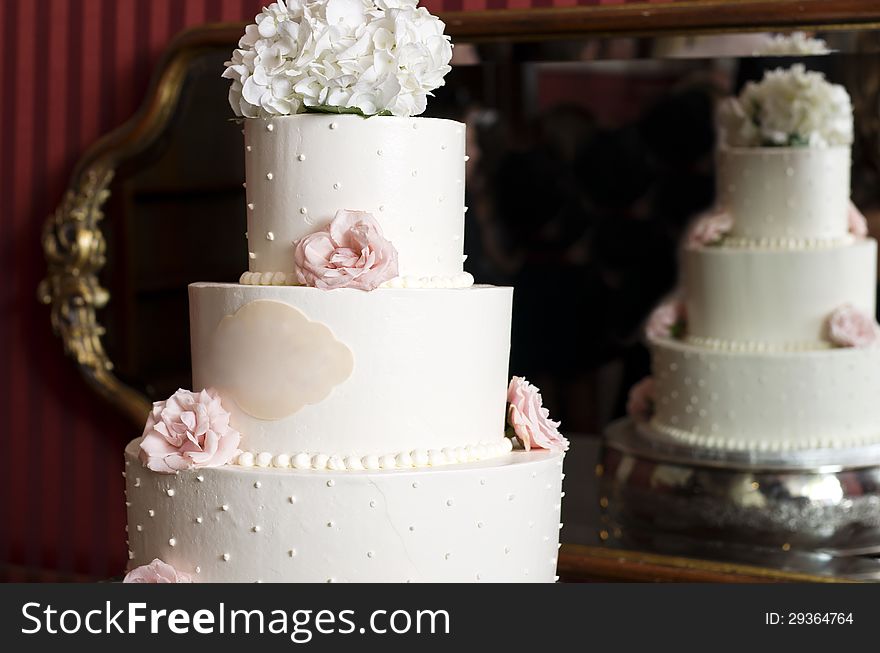 An elegant wedding cake is also reflected in the mirror. An elegant wedding cake is also reflected in the mirror.