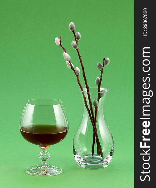 A glass of red wine and a transparent vase with willow sprigs. A glass of red wine and a transparent vase with willow sprigs