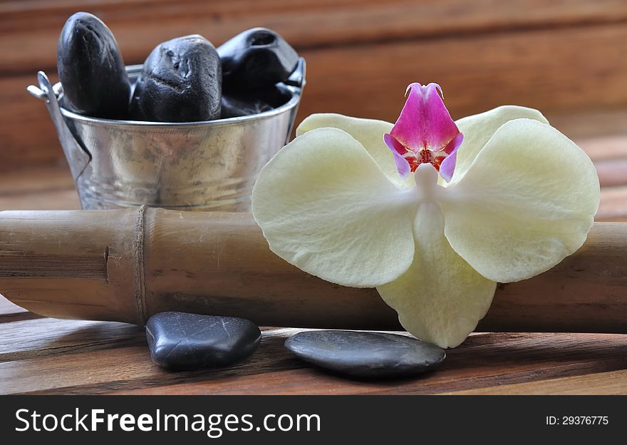 Orchid flower and massage stones on wooden  background