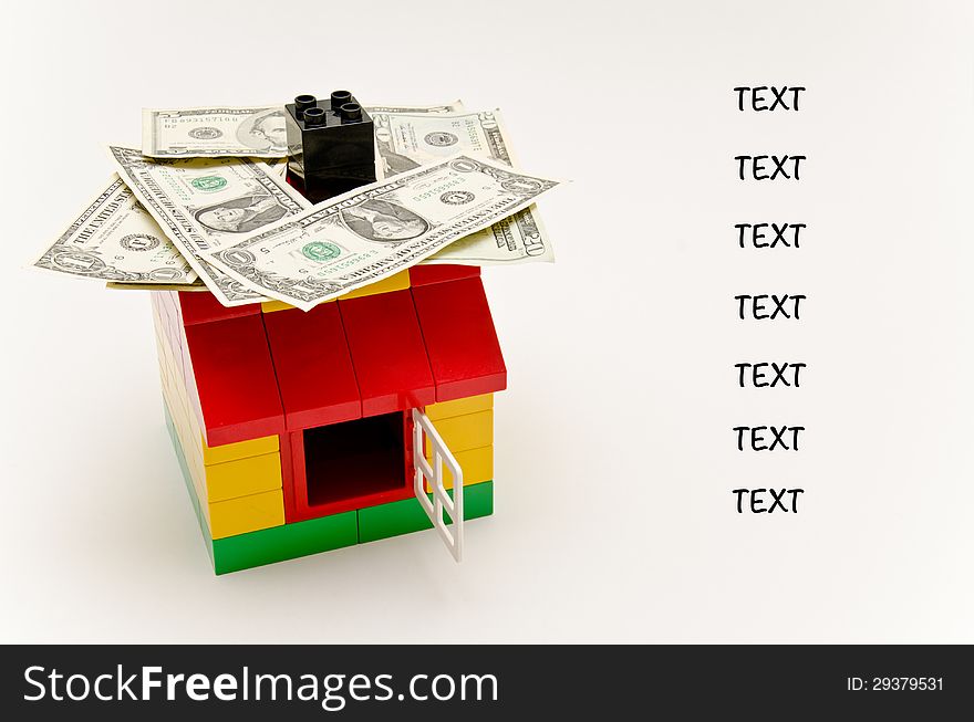LEGO house and money. Dollars on the roof. Text next to the house.