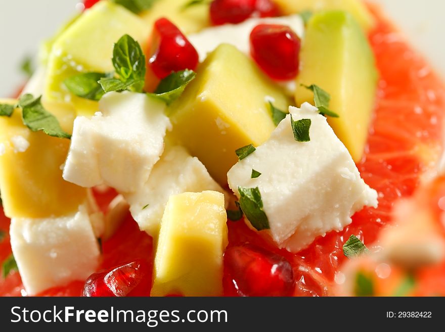 Avocado salad with goat cheese, grapefruit and pomegranate seeds, close up