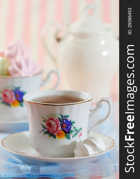 Black tea in elegant cup with colorful meringue cookies. Black tea in elegant cup with colorful meringue cookies