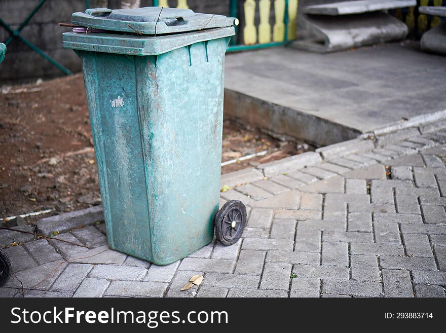 Green trash cans are on the side of the road. It looks worn out with the color starting to fade. Green trash cans are on the side of the road. It looks worn out with the color starting to fade.