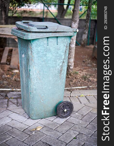 Green trash cans are on the side of the road. It looks worn out with the color starting to fade. Green trash cans are on the side of the road. It looks worn out with the color starting to fade.