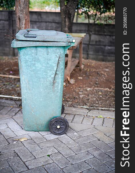 Green trash cans are on the side of the road. It looks worn out with the color starting to fade. Green trash cans are on the side of the road. It looks worn out with the color starting to fade.