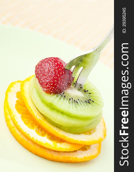 Sliced orange, kiwi fruits and strawberry on a fork. Sliced orange, kiwi fruits and strawberry on a fork