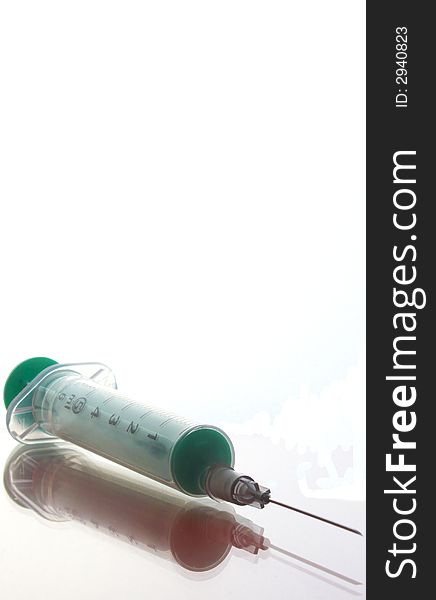 Medical syringe with a green piston. It's glass, we see it reflected. Medical syringe with a green piston. It's glass, we see it reflected.