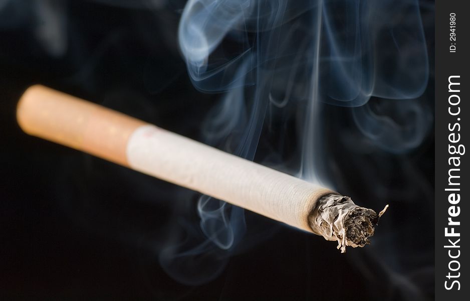 An isolated lit cigarette on black background