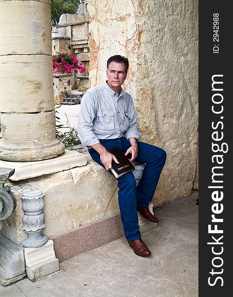 A man with a serious expression on his face, sitting with a bible in his hands. A man with a serious expression on his face, sitting with a bible in his hands.