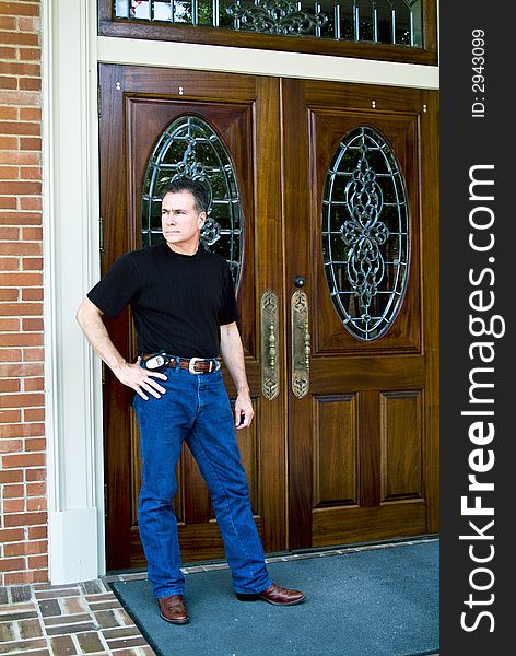 Man standing in front of beautiful wooden double doors with ornate glass work. Man standing in front of beautiful wooden double doors with ornate glass work.