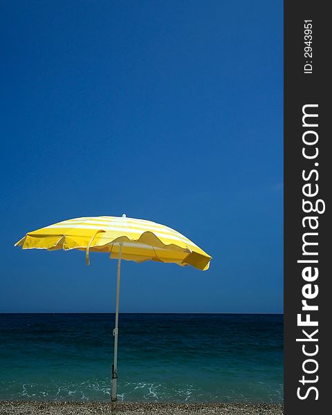 Yellow parasol on beach in Greece