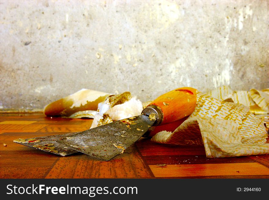 Two palette knifes with tattered wall paper.