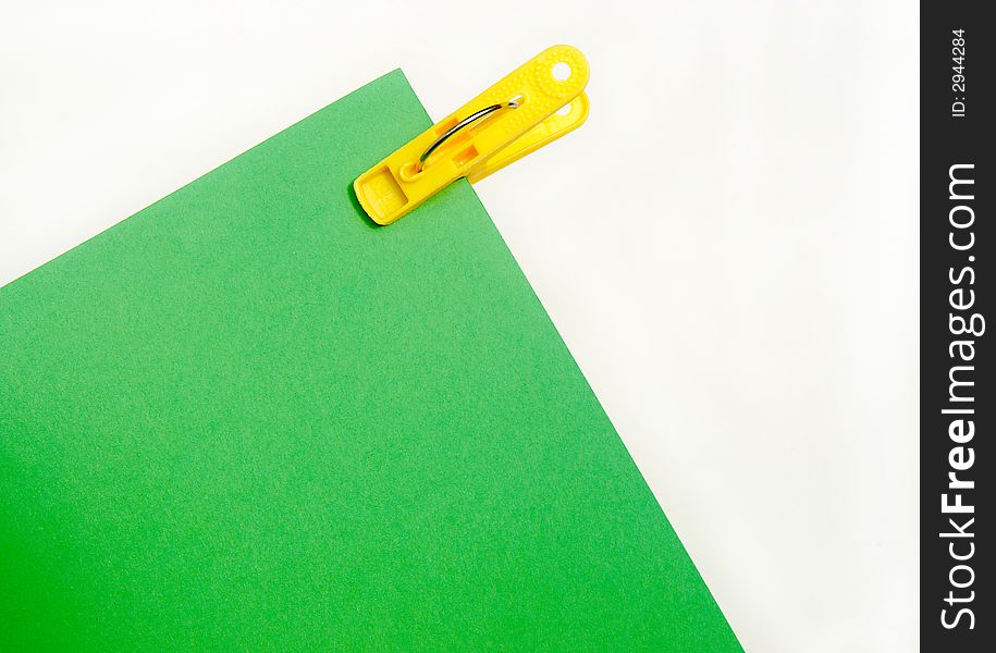 Bright yellow clip and piece of green paper in school or office stationery. Bright yellow clip and piece of green paper in school or office stationery