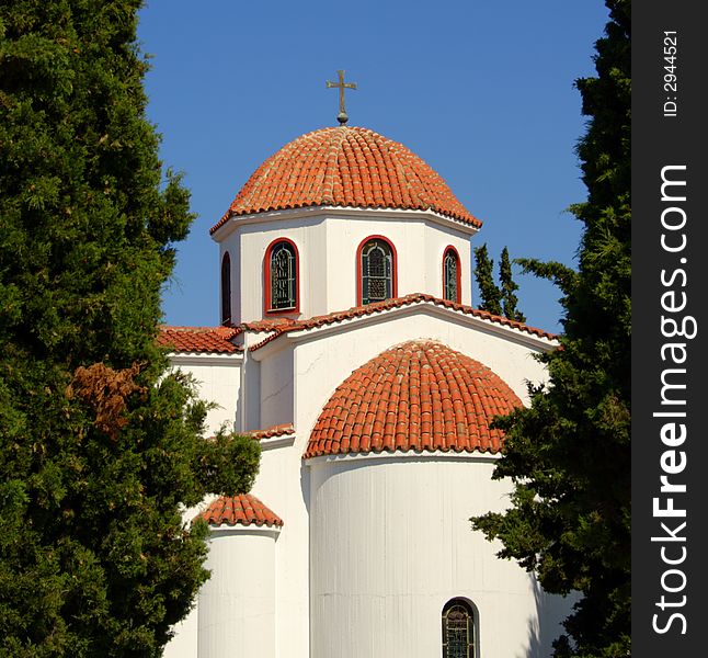 White church in Greece with green trees