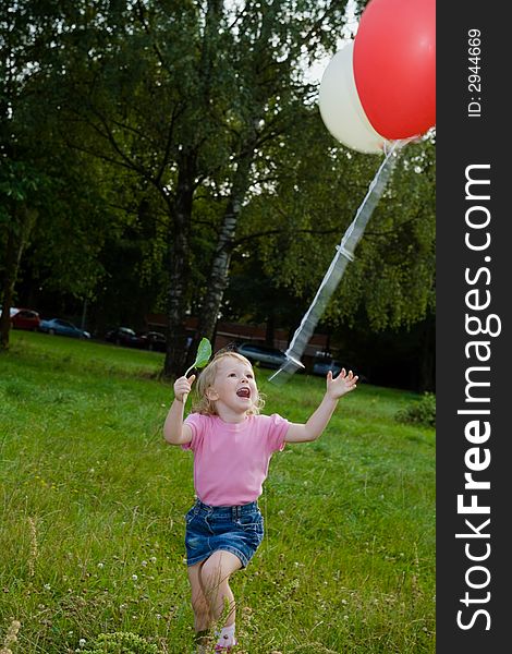 Girl with balloon runs on lawn