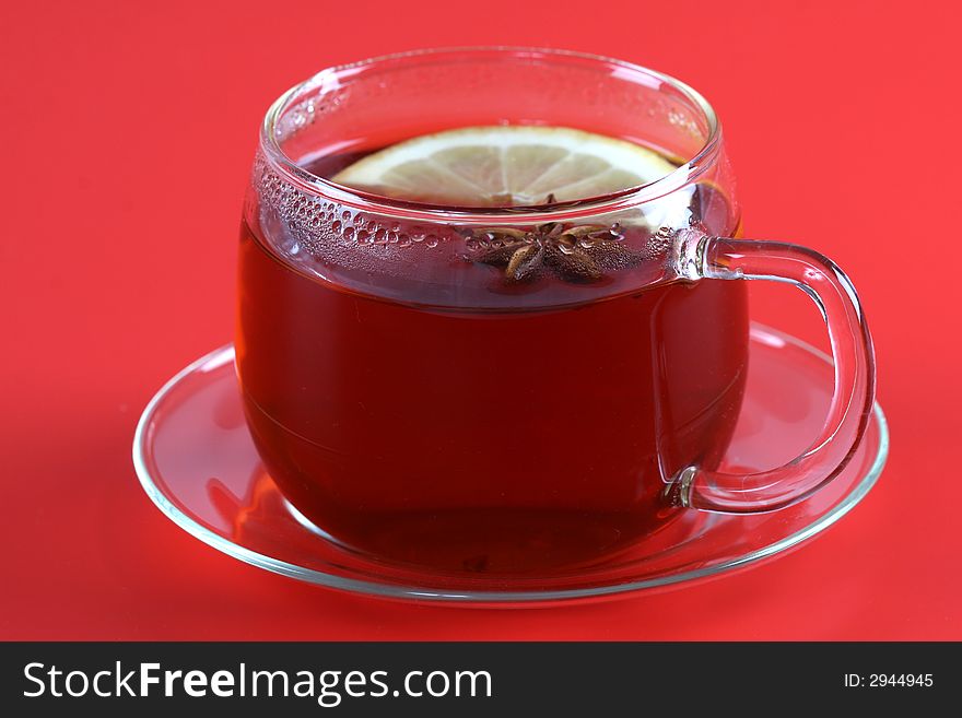 Cup of tea with anise lemon on red background