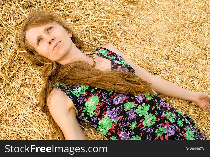 The red girl lays on straw and looks at the sky. The red girl lays on straw and looks at the sky