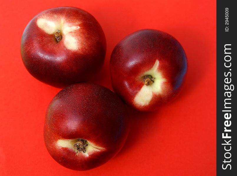 Three Juicy red ripe nectarines on red background. Three Juicy red ripe nectarines on red background