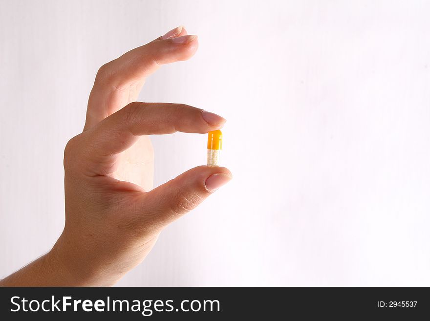 A pill between fingers over a white background!. A pill between fingers over a white background!