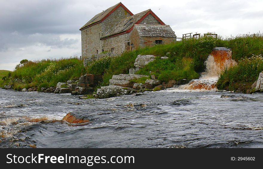 Old mill and water race in spate under storm clouds and in the rain. Old mill and water race in spate under storm clouds and in the rain.