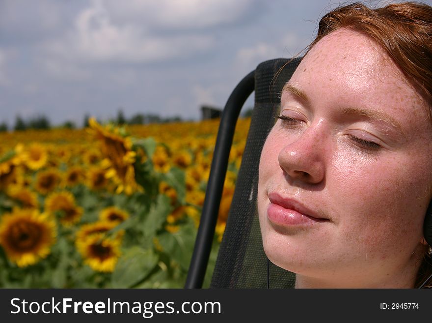 A young lady relaxing by a field of sunflowers. A young lady relaxing by a field of sunflowers