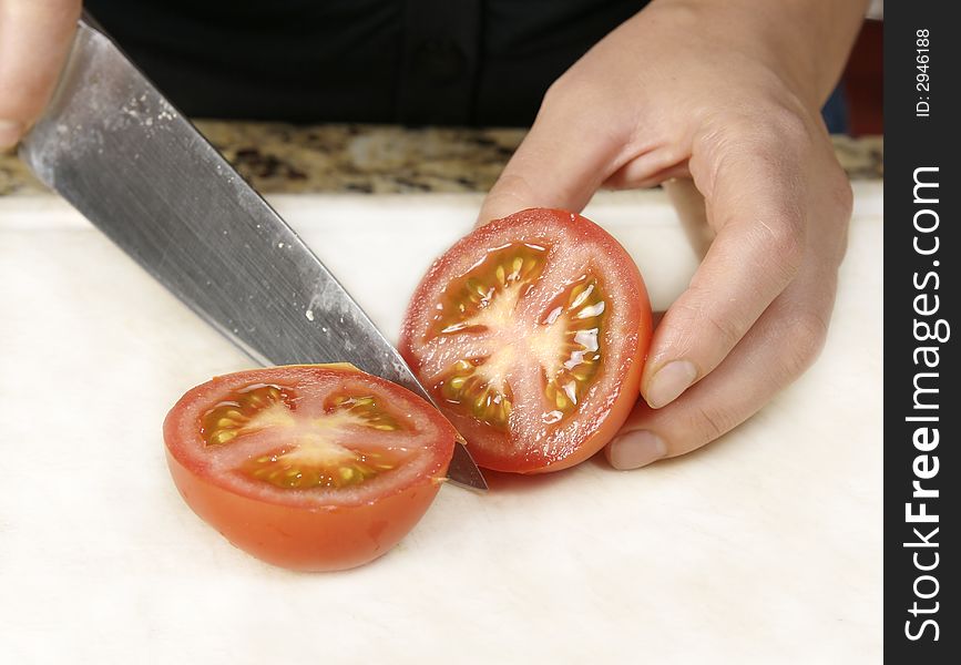 Cutting a red tomato for a meal using a knife. Cutting a red tomato for a meal using a knife.