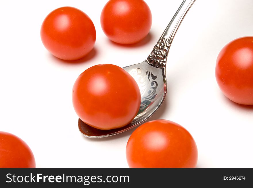 Red tomatoes on white background and teaspoon. Red tomatoes on white background and teaspoon