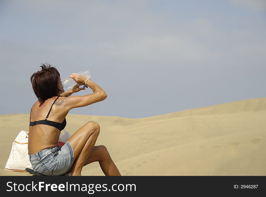 Woman is drinking water in the desert. Woman is drinking water in the desert