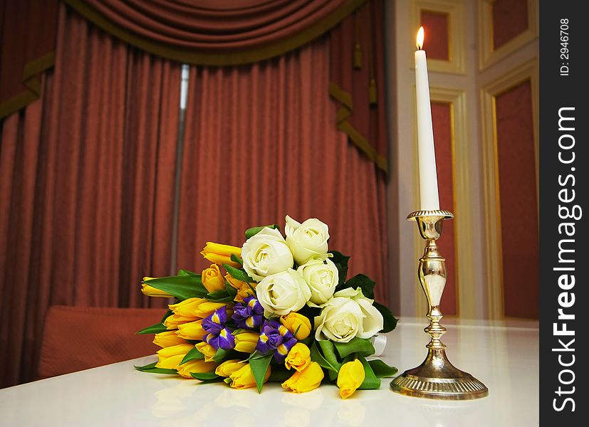 Bouquet with roses near a candle