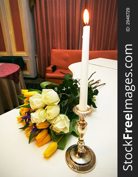 Bouquet with roses near a candle