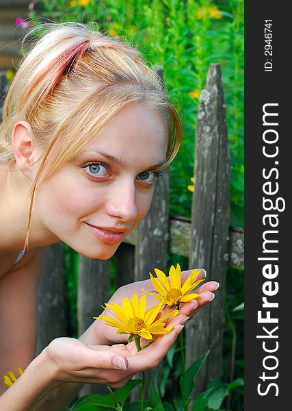 The girl holds yellow flowers in hands on nature. The girl holds yellow flowers in hands on nature