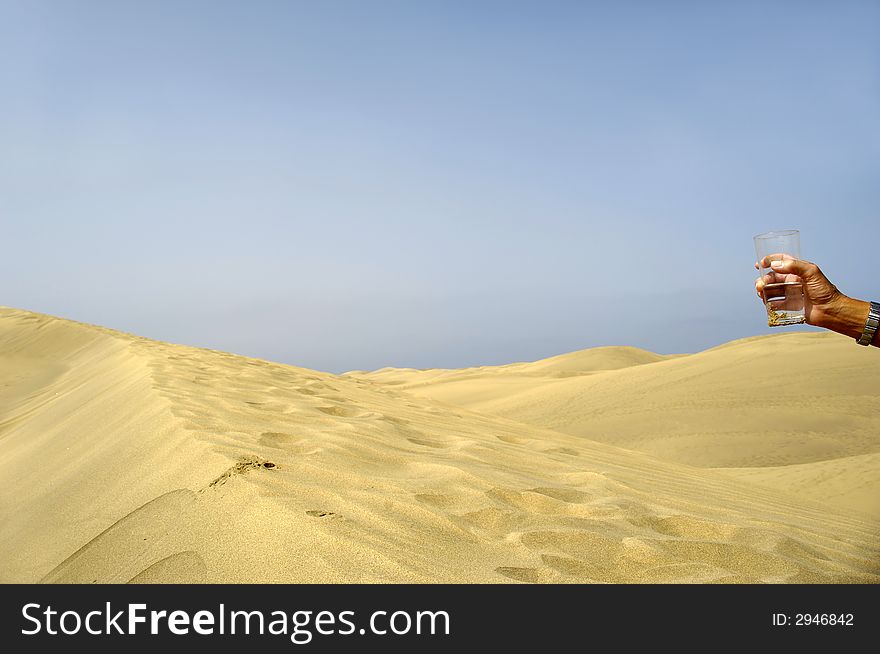Hand is holding for a fresh glass of cold water in desert. Hand is holding for a fresh glass of cold water in desert.