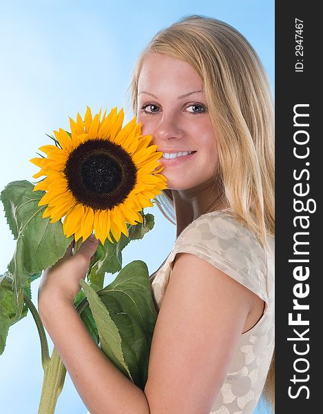 The attractive blonde in studio holds a sunflower in hands. The attractive blonde in studio holds a sunflower in hands