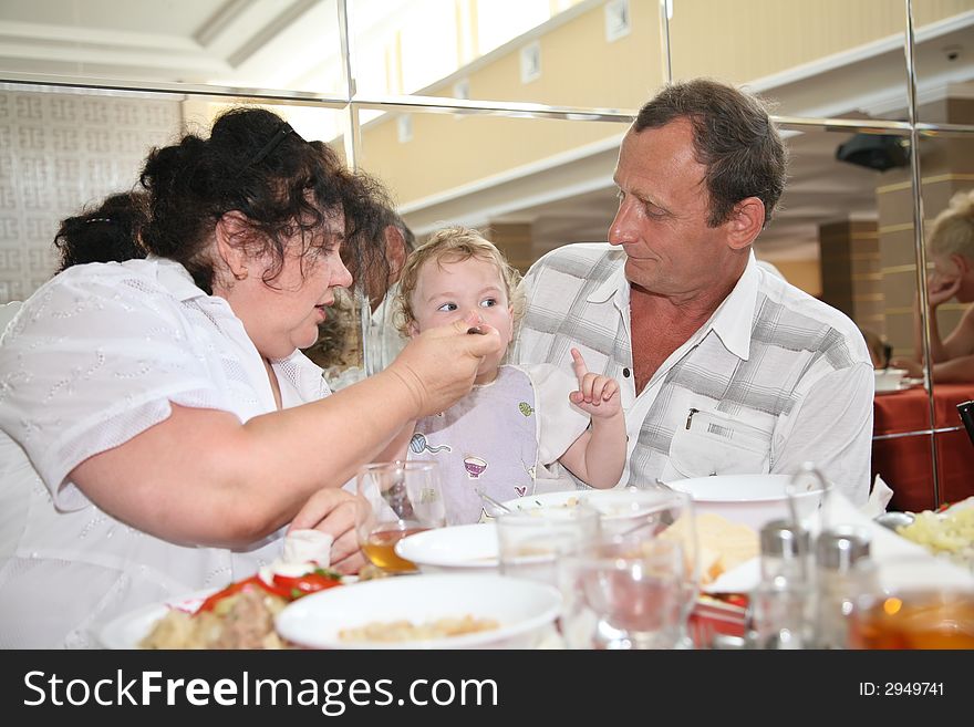 Grandmother with grandfather feeds child in canteen one. Grandmother with grandfather feeds child in canteen one