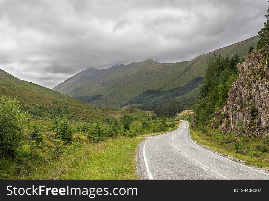 Empty road in the middle of scottish highland during a summer day with cloudy sky. Empty road in the middle of scottish highland during a summer day with cloudy sky