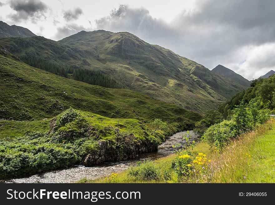 Mountain view in Scotland a summer day. Small river in the middle of mountains. Mountain view in Scotland a summer day. Small river in the middle of mountains